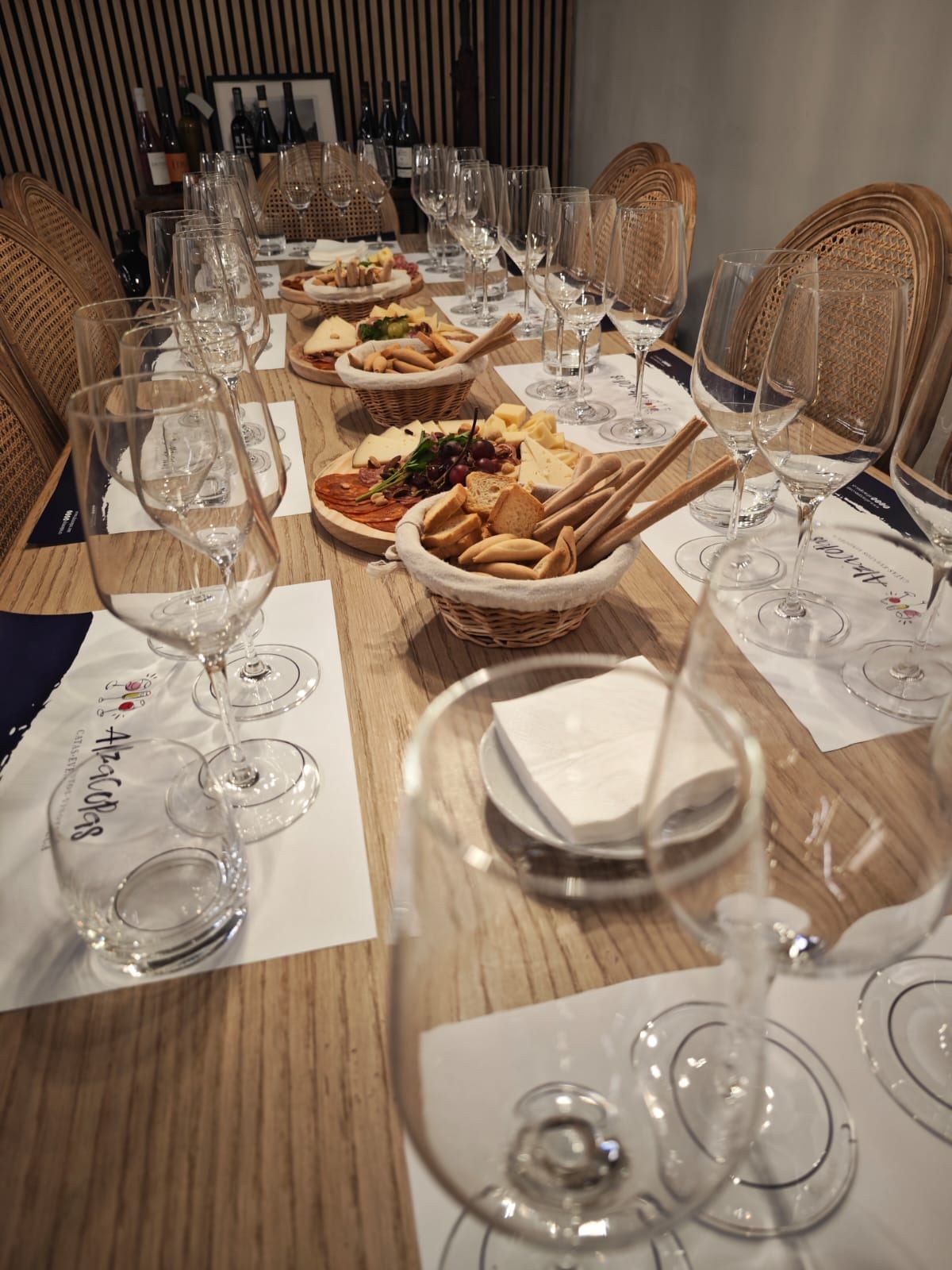 Mesa larga preparada con copas y tablas de quesos